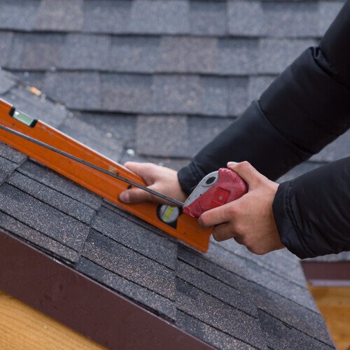 close-up of a roofer working on a shingle roof